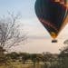 a hot air balloon flying over a lush green field