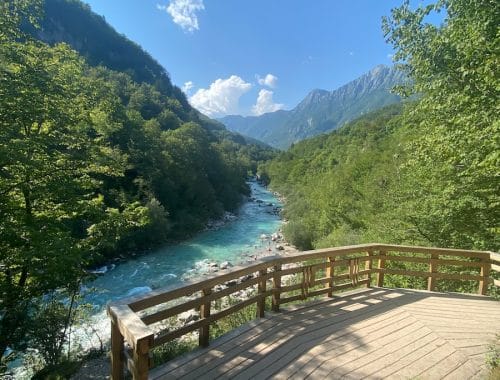 a wooden deck overlooks a river and mountains