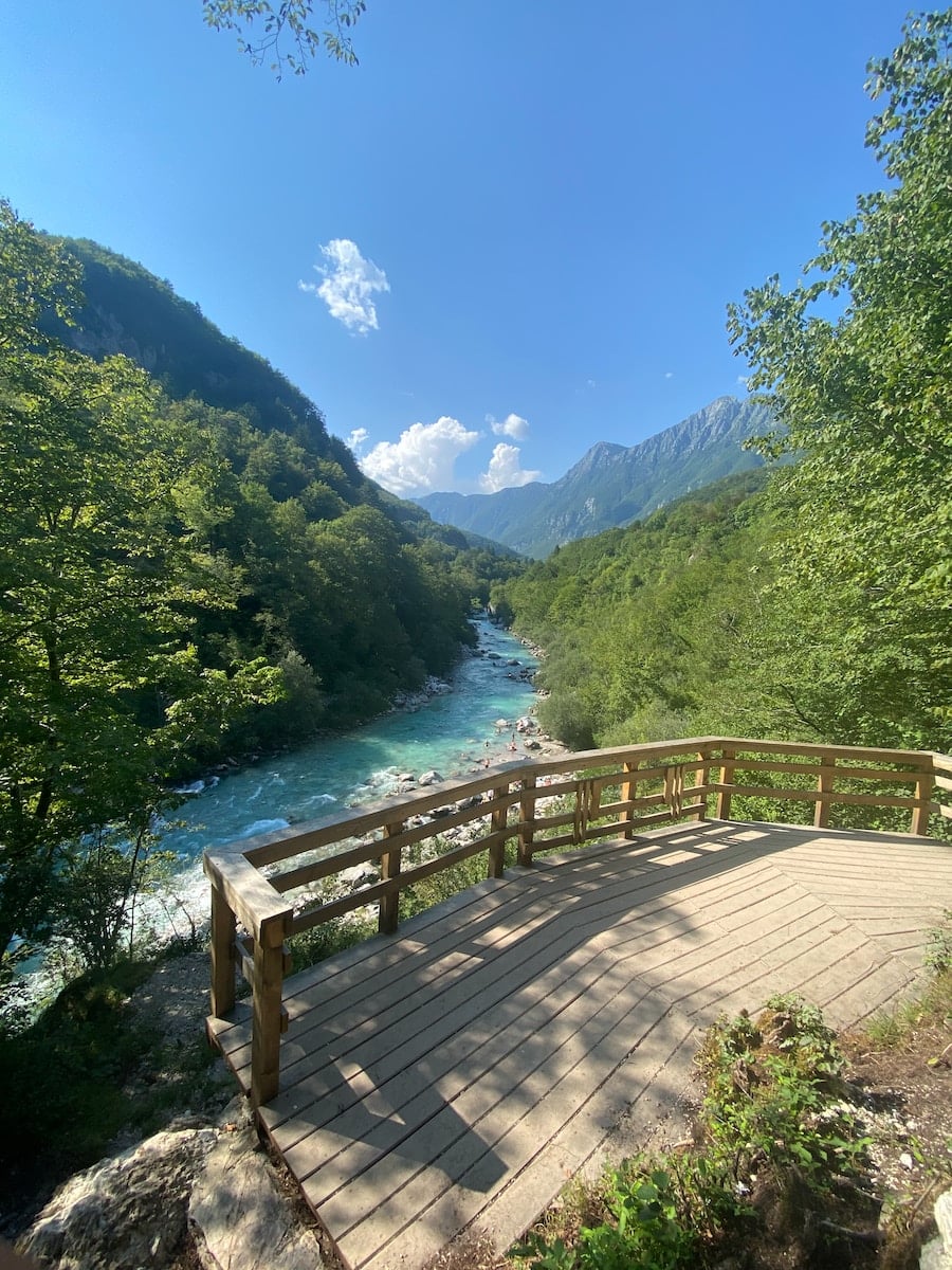 a wooden deck overlooks a river and mountains